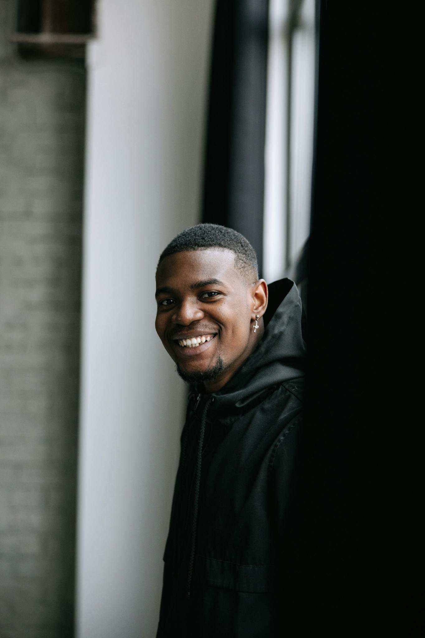 Portrait of a smiling man indoors with natural light and soft tones.